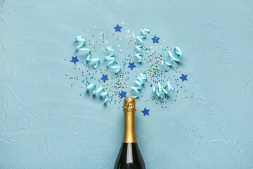 Christmas composition with bottle of champagne and decor on blue background