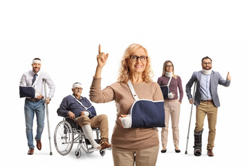 Woman with injured arm wearing a sling and pointing up in front of other people with injuries
