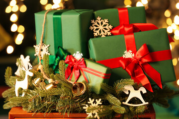 Christmas composition with gifts and decorations on wooden table against blurred lights, closeup