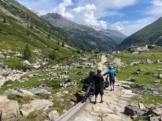 Fototapeta premium Mountainbiker schieben ihr Fahrrad bergab in den Zillertaler Alpen in der Nähe vom Pfitscherjoch in Österreich