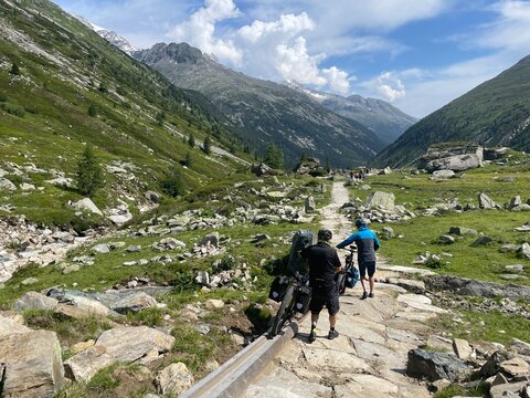 Mountainbiker schieben ihr Fahrrad bergab in den Zillertaler Alpen in der Nähe vom Pfitscherjoch in Österreich