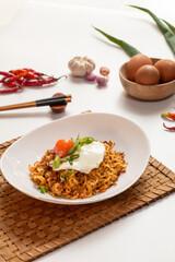 Indomie Bangladesh made from special ingredient spicies served on plate with napkin, chopstick, egg, fried onions and ingredient on the side. noodle bangladesh. mie bangladesh viral. white background