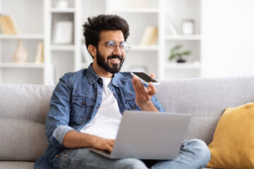 Young Indian Man Using Smartphone For Recording Voice Message At Home