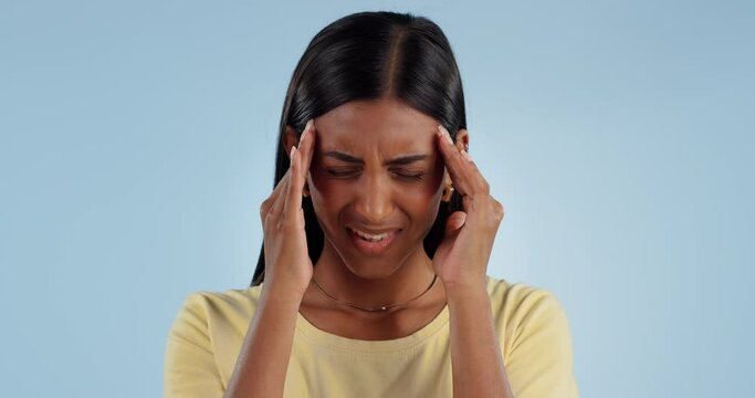 Stress, headache and Indian woman in studio with pain, inflammation and fatigue with anxiety. Mental health, burnout and person with head pain, migraine and problem for crisis on blue background