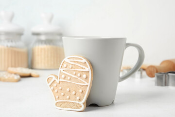 Tasty Christmas cookie and cup of drink on light background