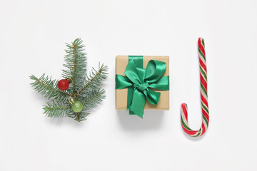 Gift box, fir branch with Christmas balls and candy cane on white background