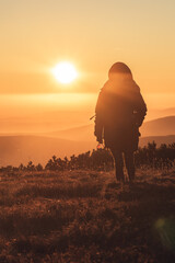 Woman walking on a mountains peak when sun is going down, beautiful sunset in Krkonose, Czech republic