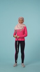 Fototapeta na wymiar Full-sized isolated photo capturing an attractive young woman wearing a sportswear and a hijab, sheila. She is measuring her waist, smiling at the camera.