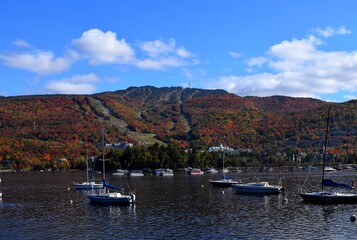 view across lake Tremblant towards the village and ski slopes of Mont-Tremblant, seen in beautiful Autumn colours