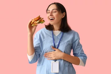 Fotobehang Young female doctor with tasty sandwich on pink background © Pixel-Shot