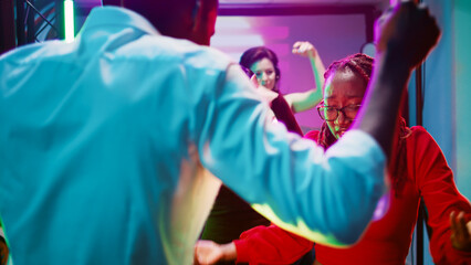 Happy couples dancing in pairs at club, showing dance moves on modern clubbing music. Dance partners having fun on dance floor and enjoying night out with friends. Handheld shot.