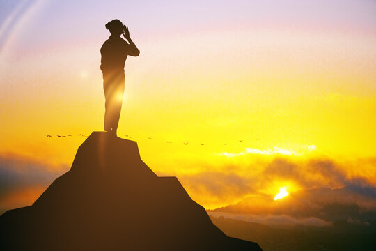 Silhouette of woman standing on abstract mountain top at sunset.