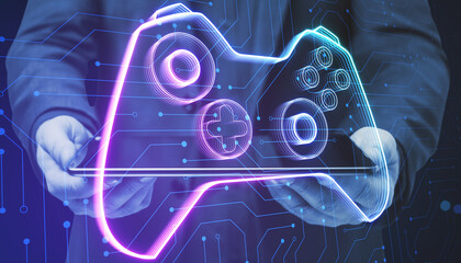 Close up of businessman hand holding creative joystick or gamepad hologram on blurry background. Esport, gaming and fun concept. © Who is Danny