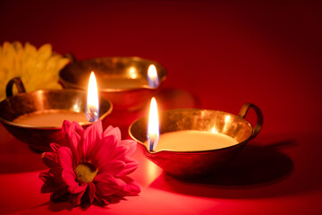 Obraz na płótnie Canvas Happy Diwali. Traditional Hindu celebration. Diya oil lamps and flowers on red background. Religious holiday of light.