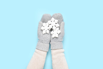 Female hands in warm mittens with beautiful Christmas decorations on color background, closeup