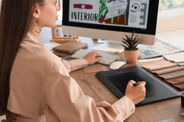 Female interior designer working with graphic tablet at table in office, closeup