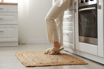 Woman on wicker carpet in light kitchen