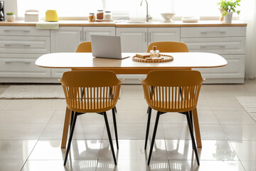 Interior of light kitchen with white counters and dining table