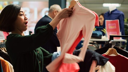 Asian woman pick clothes in a hurry to benefit from black friday seasonal sales and special offers....