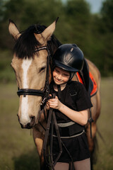 Portrait of a young jockey with a horse, horse riding training, a boy stroking a horse, a lesson for a young jockey in an equestrian school or club, pet
