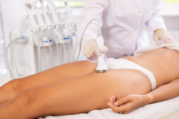 Hip massage with vibration attachement of beauty machine to female patient.