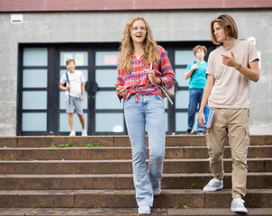 Teenagers coming home after classes in school and going through campus.