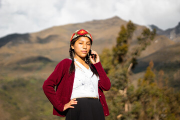 Foto de una feliz campesina caucásica hablando por teléfono inteligente puesta una chopa tejido a mano .campesina con ropa típica artesanía peruana a mano en un atardecer en los Andes peruanos. Mujer - obrazy, fototapety, plakaty