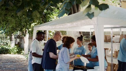 Volunteers serving free food to the needy at an outdoor event. This non-profit organization offers humanitarian aid and fosters community, helping the hungry and homeless. Aerial, handheld.