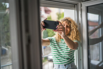 woman at the window use mobile phone take selfie photo self portrait
