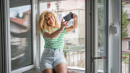 woman at the window use mobile phone take selfie photo self portrait