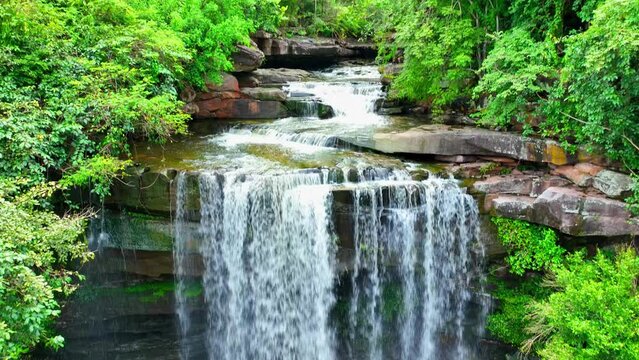 Captivating view of an epic, lush forest paradise with a stunning waterfall cascading through nature's beauty. Thung Na Muang Waterfall, Pha Taem National Park, Thailand. Exotic Getaways concept.
