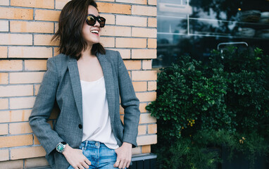 Positive female standing by brick wall