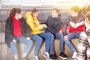 Four cheerful teenage friends having fun while spending time together outdoors on warm spring day