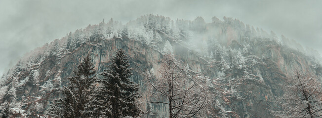 Mountain winter landscape with cloudy sky. Snowy mountain peaks in gray clouds.Austria. Hohe...