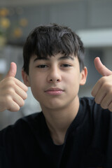 boy showing thumb up with short hair and black shirt.