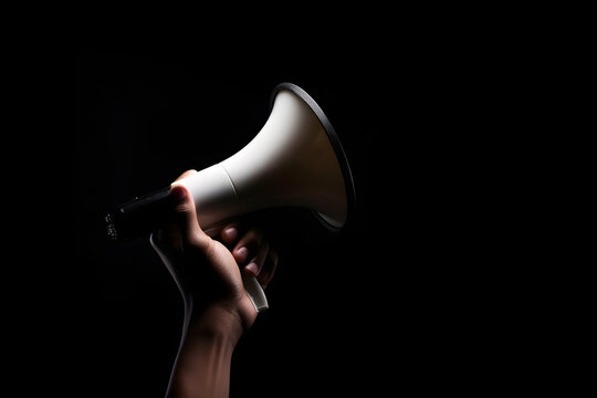 Hand holding megaphone isolated on black background with copyspace. Advertisement mock up, clip art, announcement and communication creative banner background concept