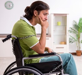 Young male invalid in wheel-chair suffering at home