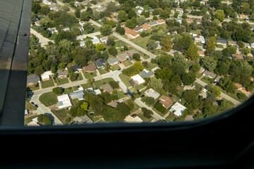B-24 bomber in a right bank over the suburbs of Tulsa, Oklahoma with the aircraft shadow on the ground below it