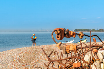 sea kayaker and kayaks  on an artifical beach made of  jumbled weathered construction waste shot on...