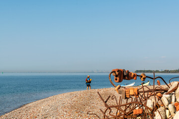 Walking the shore line: sea kayaker and kayaks on an artifical beach made of jumbled weathered construction waste shot on the leslie street spit toronto blue sky room for text