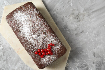 Tasty chocolate sponge cake with powdered sugar and currant on light grey textured table, top view. Space for text