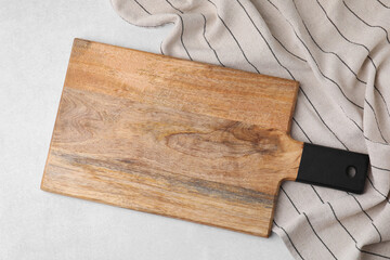 One wooden cutting board and tablecloth on light grey table, top view. Cooking utensil