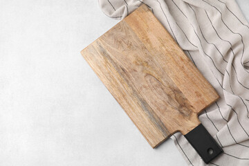 One wooden cutting board and tablecloth on light grey table, top view with space for text. Cooking utensil