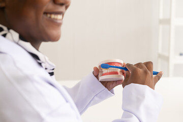 African American dentist. The dental care woman doctor showing up how to brush dental teeth model...