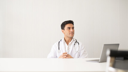 Hispanic physician wearing stethoscope in the clinic. Healthcare and medicine doctor working on laptop. Hospital specialist with medical examining.