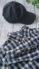 チェックのシャツとキャップ｜白い木目背景