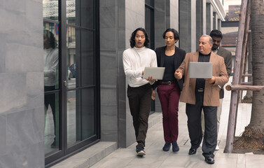 Business team meeting. A group of diversity businessman people colleagues talking while walking against contemporary corporate buildings in the city.
