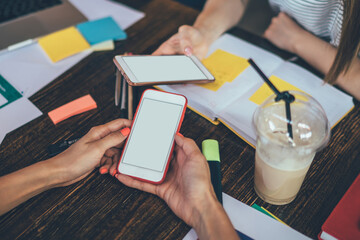 Crop colleagues with smartphones in cafe