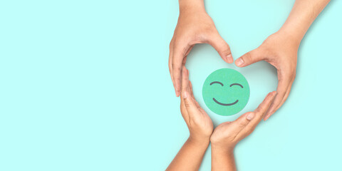 paper cut smiley face in hands make heart symbol for protection around on green background....