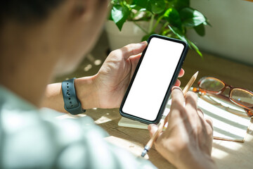 Close up view young man hands holding smart phone empty screen while sitting at workplace.